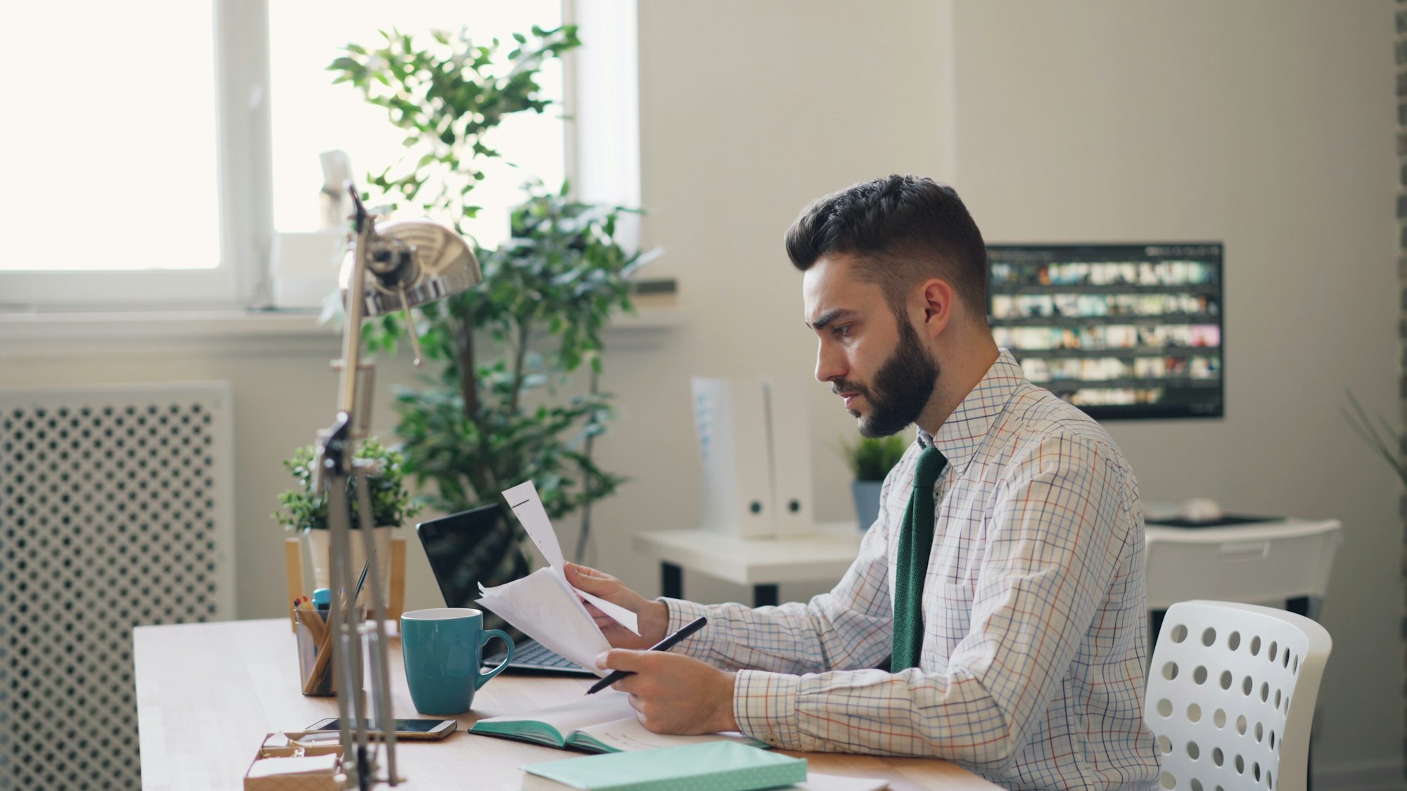 A business owner reviewing printed financial papers at a bright desk beside a laptop