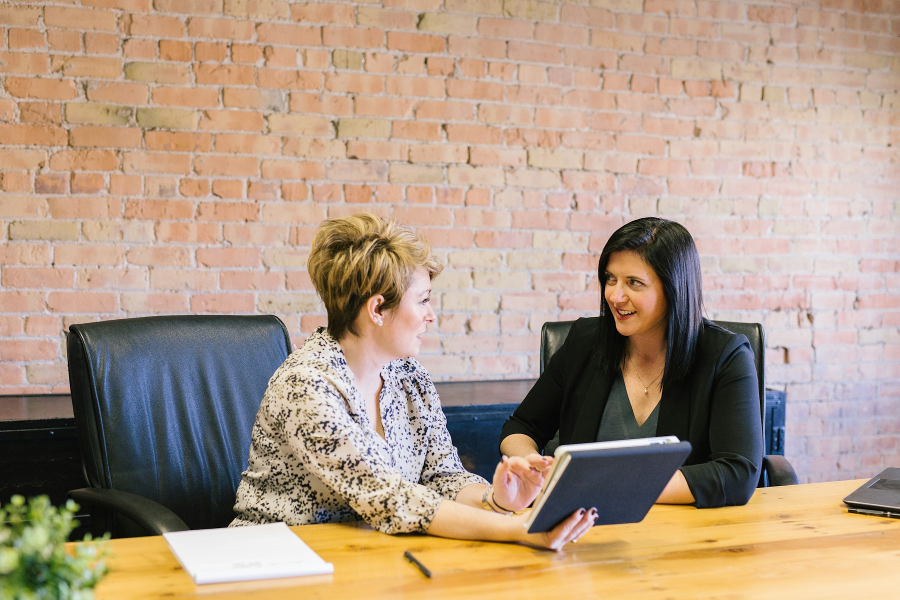 Two people talking through a plan at a wooden table