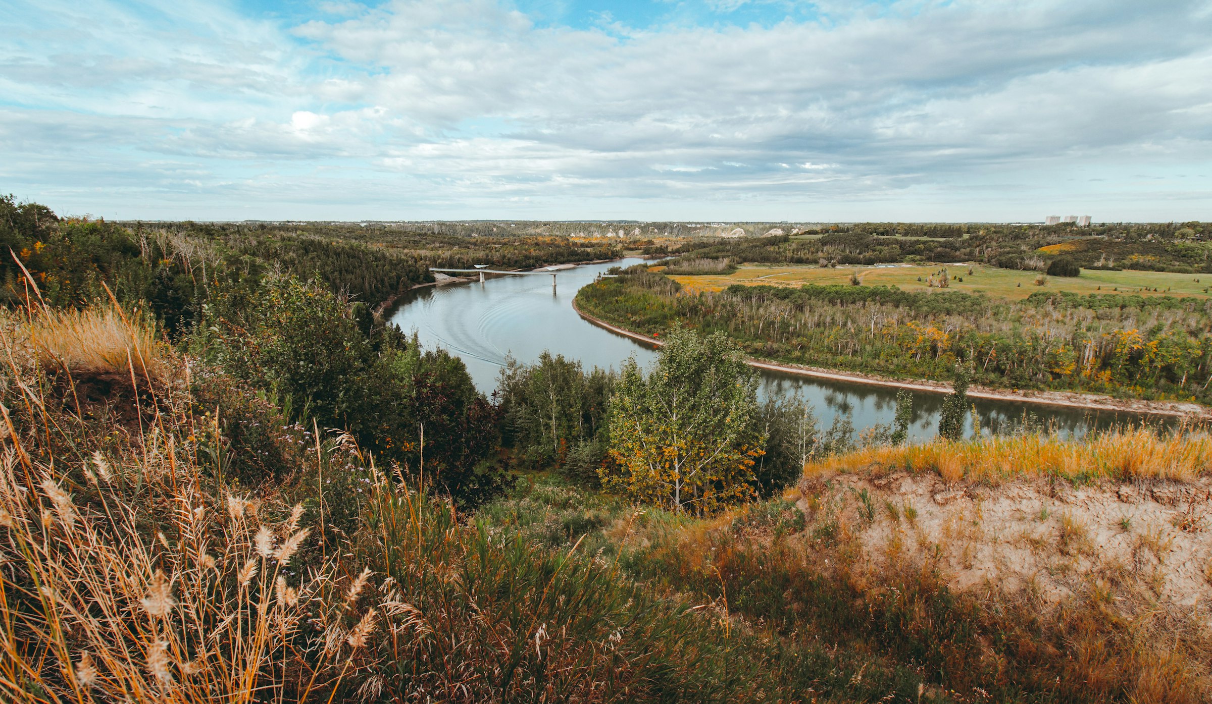 A wooded river valley under a cloudy sky