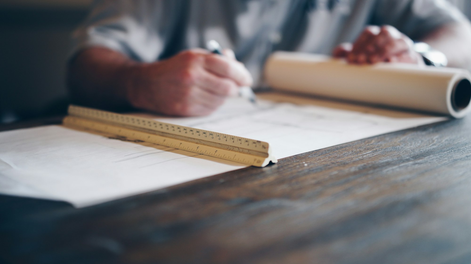 Hands marking up building plans with a scale ruler