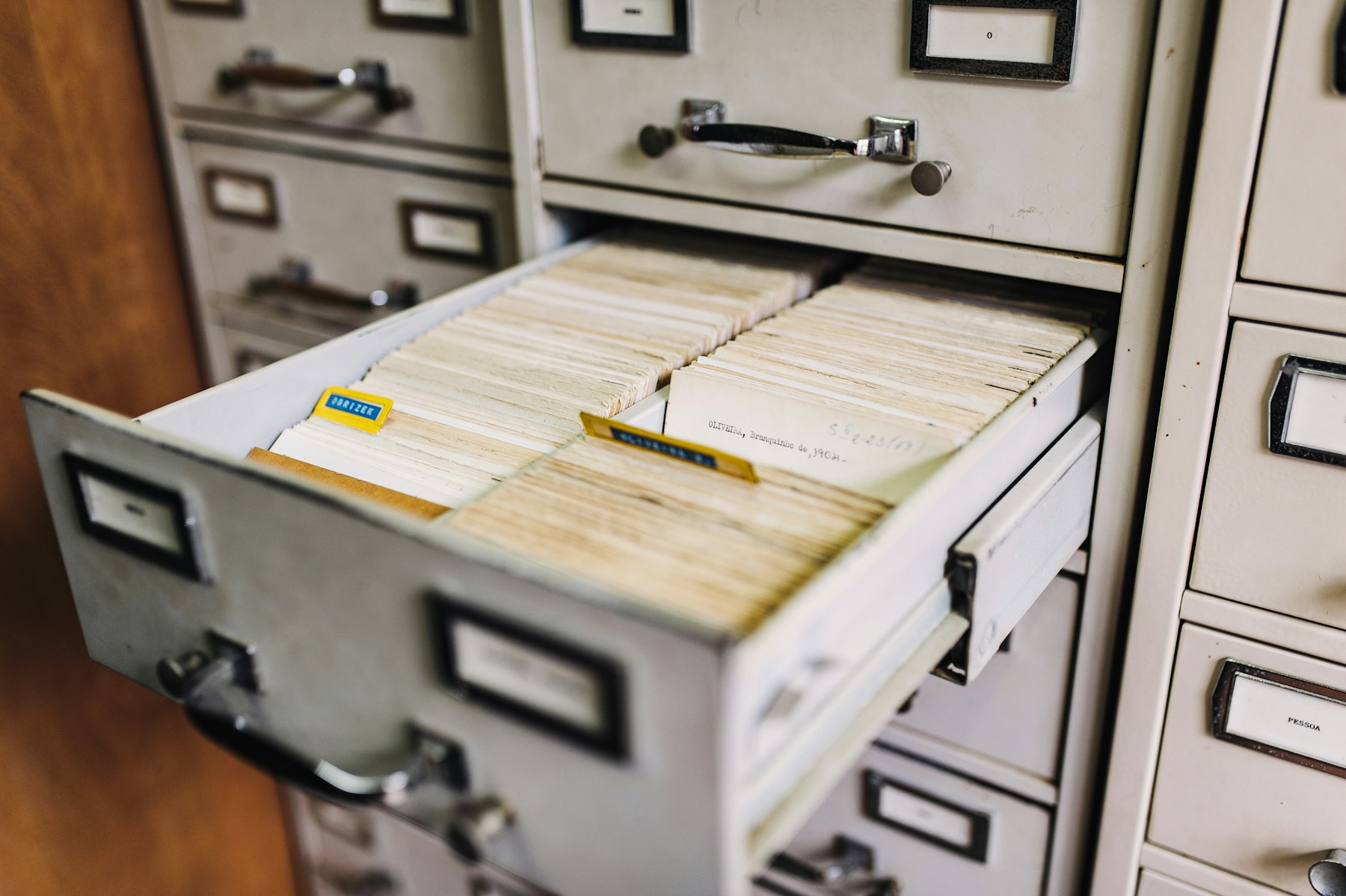 A metal filing cabinet with a drawer of index cards open