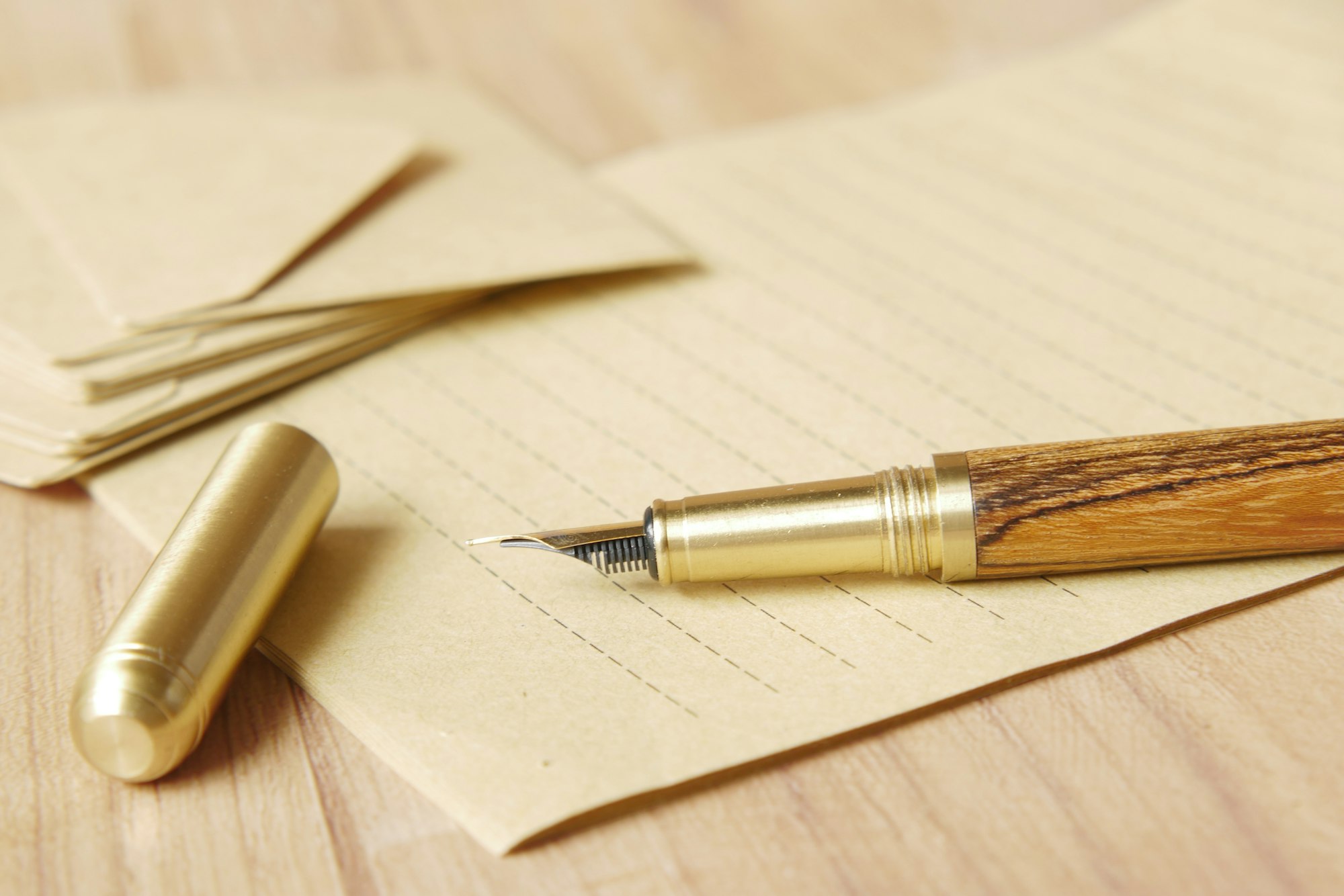 A fountain pen on lined paper beside a stack of envelopes on a wooden desk
