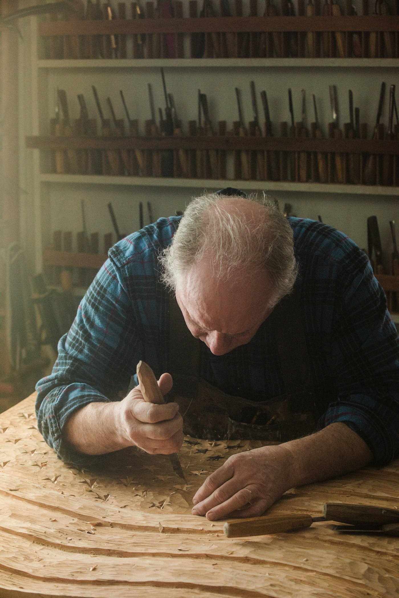 A craftsman carving a wooden panel in his workshop